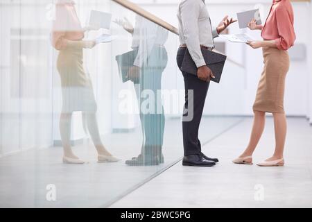 Portrait en coupe basse d'un homme d'affaires afro-américain méconnu qui parle à une jeune femme tout en se tenant debout sur un balcon dans un immeuble de bureaux, un espace de photocopie Banque D'Images