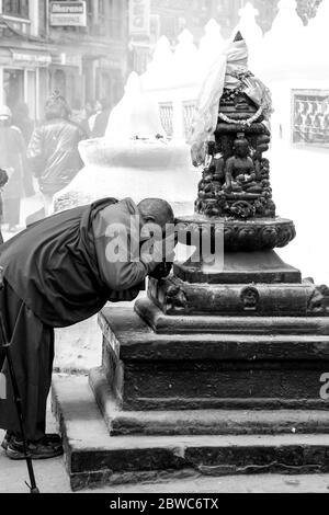 Vieux moine priant à une statue de Boudnath Banque D'Images