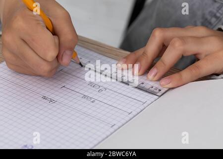 L'étudiant utilise une règle et un crayon pour tracer des lignes qui constituent la solution à la tâche donnée dans la leçon. Banque D'Images