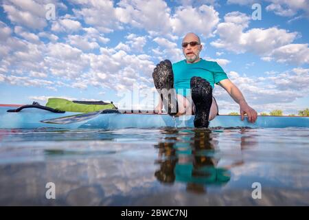 un pagayeur masculin portant cinq chaussures d'eau à cinq doigts est assis sur son stand-up paddleboard - vue à angle bas d'une caméra partiellement submergée Banque D'Images