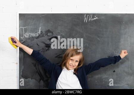 L'élève, tout en essuyant le tableau, a soulevé les mains et s'est tourné vers les élèves de la salle de classe Banque D'Images