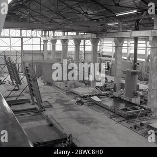 Années 1960, vue historique sur l'intérieur d'une grande usine viennent entrepôt de fabrication de panneaux en béton précoulé, pour l'utilisation dans les blocs de tour modernes de haute hauteur 'Brutaliste' en cours de construction à cette époque, Angleterre, Royaume-Uni. Les mouds à la font les panneaux de béton peuvent être vus sur le plancher du bâtiment. Banque D'Images