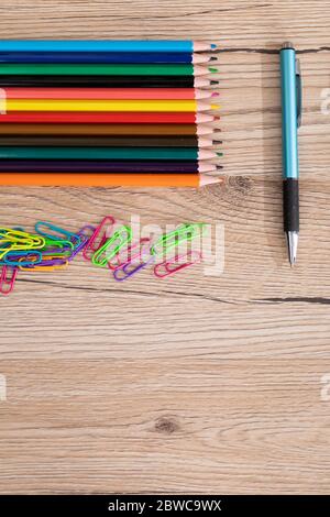 Des trombones et des crayons de couleur se trouvent sur un bureau en bois. Nouveaux accessoires scolaires. Banque D'Images