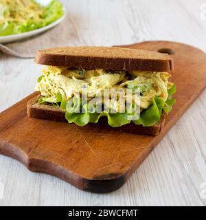 Sandwich au poulet Coronation maison sur un bois rustique sur une surface en bois blanc, vue latérale. Gros plan. Banque D'Images