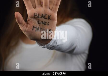 Une femme caucasienne tient la main avec du texte Black Lives Matter en soutien des manifestations pacifiques contre la brutalité policière et le racisme Banque D'Images