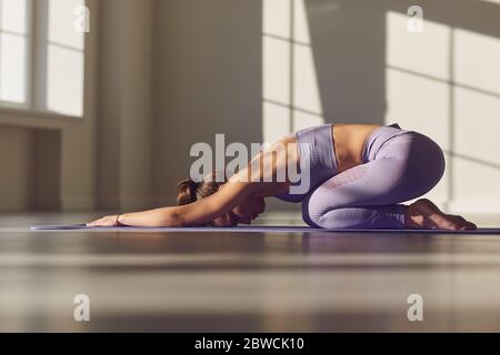 Fille de yoga. Une femme sportive séduisante pratique le yoga. Se détend. Médite dans une salle ensoleillée le matin au lever du soleil. Banque D'Images