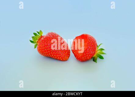 deux fraises avec feuilles de fraises sur fond gris. Baies entières et mordides. Vente, cuisine Banque D'Images