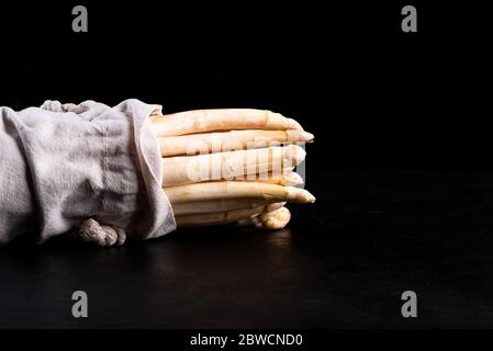 Asperges blanches dans un sac de tissu sur un asperge blanche noire background.Organic. Banque D'Images