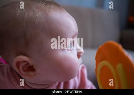 Gros plan de la petite fille qui joue avec des jouets à cercle jaune dans le marcheur de bébé Banque D'Images