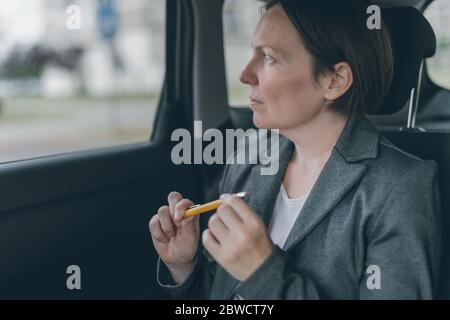 Businesswoman waiting at car siège arrière et jouer avec le crayon pour vaincre l'anxiété Banque D'Images