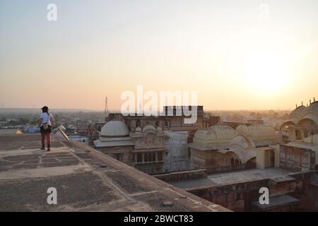 Voyageur seul, une jeune femme dans ses années 20, marchant sur le toit et apprécie la vue sur le coucher du soleil de la ville. Photo prise en Inde. Banque D'Images