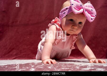 Mignon bébé fille porter adorable chapeau faire pousser dehors, regardant l'appareil photo et sourire sur fond rouge Banque D'Images