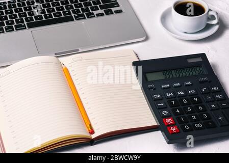 Calculatrice, agenda, ordinateur portable ouvert, une tasse de café et un ordinateur portable sur le bureau. Comptabilité, finances et affaires. Banque D'Images