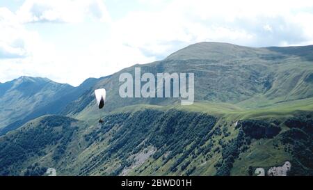 Parapente volant au-dessus des montagnes pendant la journée d'été - Géorgie, kazbegi Banque D'Images