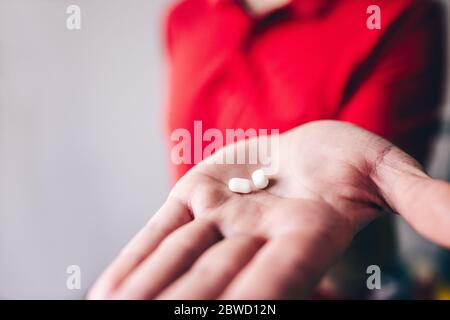 Vue en coupe de la main d'un homme tenant deux bonbons enrobés de sucre. Guy en chemise rouge montrer sur l'appareil photo. Délicieux en-cas délicieux. Banque D'Images