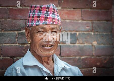 PATAN, LALITPUR, NÉPAL - 15 AOÛT 2018 : un homme âgé non identifié de nouveau-né est assis devant le Palais royal de Mul Chowk, sur la place Patan Durbar - Népal Banque D'Images