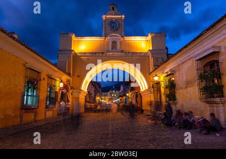 Exposition longue la nuit avec flou de mouvement des gens par l'Arc de Santa Catalina, Antigua, Guatemala. Banque D'Images