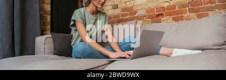 vue rognée d'une jeune femme à l'aide d'un ordinateur portable, assis sur un canapé à la maison, image horizontale Banque D'Images
