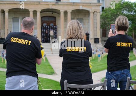 Winterset, Iowa, États-Unis. 31 mai 2020. Les membres de la famille portent des t-shirts imprimés « sécurité » assortis lorsqu'ils regardent KIERNAN BLANCHARD franchir les marches du palais de justice lors de la cérémonie de remise des diplômes de l'école secondaire de Winterset, le 31 mai 2020. Les diplômés et leurs familles ont reçu deux véhicules chacun et ont reçu des blocs horaires par ordre alphabétique. Après avoir parcouru une rue fermée, les aînés ont marché jusqu'aux marches du palais de justice du comté de Madison pour recevoir la reconnaissance et leur diplôme des responsables scolaires. Les écoles Winterset ont indiqué que 146 élèves étaient admissibles à un diplôme. (Image crédit: © Frit Banque D'Images