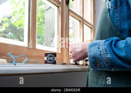 Paris, France - 30 mai 2020 : une femme se préparant à ouvrir le testeur de peinture Farrow et ball peut peindre les fenêtres de la maison récemment rénovée pendant la reconstruction Banque D'Images