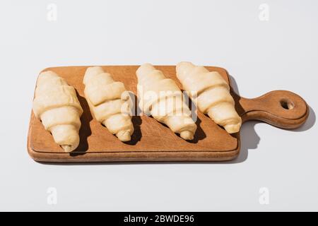 croissants frais crus sur planche à découper en bois sur fond blanc Banque D'Images