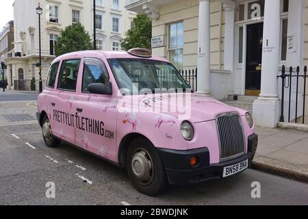 LONDRES, Royaume-Uni -16 MAI 2020 - UN taxi britannique Hackney Carriage peint en rose avec des annonces pour peu de choses dans la rue à Londres, Angleterre. Banque D'Images