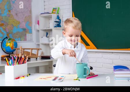 Portrait d'un garçon souriant qui fait ses devoirs en classe à l'école. Éducation. Banque D'Images