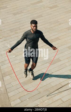 Tenue concentrée jeunes sportifs sautant avec corde à sauter lors de l'entraînement à l'extérieur Banque D'Images