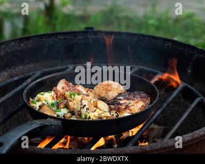 Les pommes de terre aux champignons et aux œufs et une hache de filet de dinde sont frites dans une poêle au feu Banque D'Images