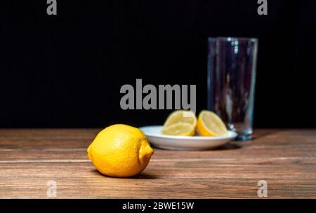 Citrons avec une tranche de citron sur une plaque de céramique et un verre derrière la préparation de la limonade Banque D'Images