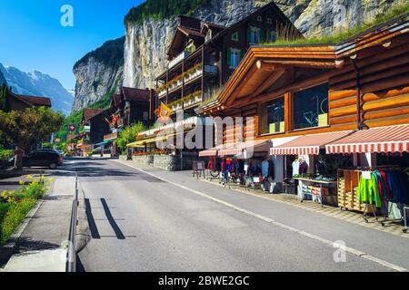 Rue charmante avec boutiques de sport et haute cascade de Staubbach en arrière-plan. Maisons traditionnelles en bois avec belle rue à Lauterbrunnen, Bernois Banque D'Images