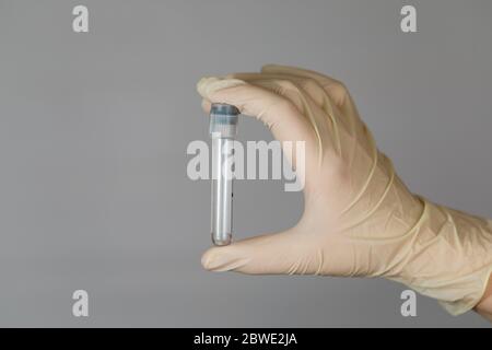 Tube à essai vide pour analyse biomatérienne dans les mains d'une infirmière. Analyse clinique de virus avec mesures de précaution. Banque D'Images