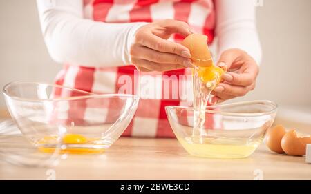 Détail des mains de femme séparant les jaunes d'œufs des blancs en deux bols en verre Banque D'Images