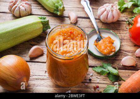 Caviar fait maison à partir de tomates et d'oignons courgettes dans un pot en verre sur fond de bois. Mise en conserve de production maison, légumes en conserve Banque D'Images