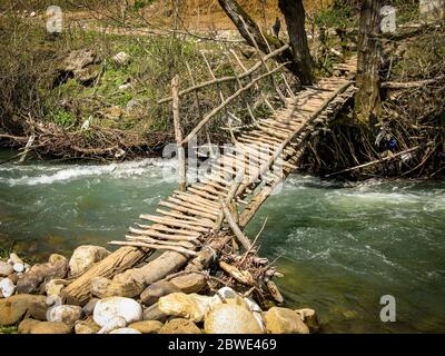 Vieux pont en bois de l'autre côté d'une rivière. Pont en bois avec une rampe sur la rivière eau courante début du printemps. Le vieux pont de parquet en bois Banque D'Images