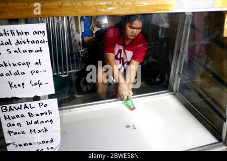Antipolo City, Philippines - 1 juin 2020 : un ouvrier nettoie et désinfecte les étagères d'un boulangshop. Banque D'Images