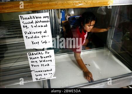Antipolo City, Philippines - 1 juin 2020 : un ouvrier nettoie et désinfecte les étagères d'un boulangshop. Banque D'Images