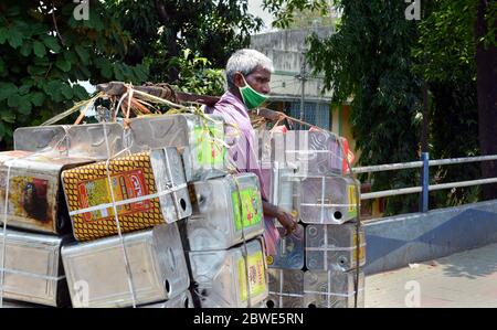 L'employé transportant des boîtes en étain pendant la période de verrouillage. Il travaille pour sa famille pour gagner de l'argent. Il porte également un masque pour sa protection. Banque D'Images