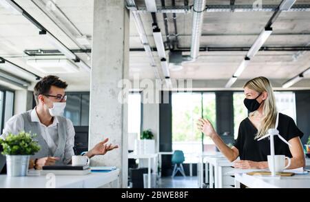 Les jeunes avec des masques de visage reviennent au travail après avoir été verrouillés. Banque D'Images