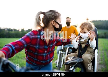 Famille avec deux petits enfants en voyage cycliste, portant des masques faciaux. Banque D'Images