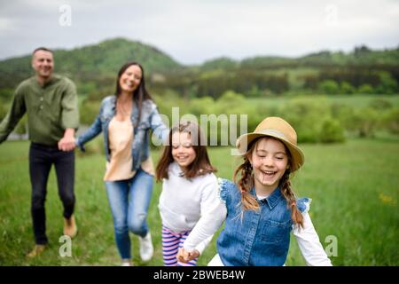 Famille heureuse avec deux petites filles qui s'exécutent à l'extérieur au printemps. Banque D'Images