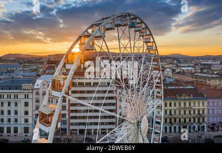 Budapest, Hongrie - vue aérienne de la célèbre grande roue de Budapest avec le château de Buda Palais Royal et un magnifique coucher de soleil et ciel dorés. La roue i Banque D'Images