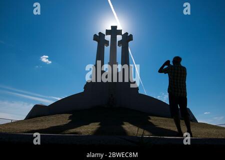 Un touriste prend une photo du monument rétroéclairé, les trois croix. À Vilnius, Lituanie. Banque D'Images