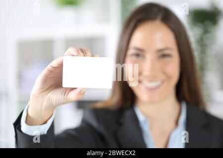 Vue de face d'une femme de direction heureuse montre une carte de crédit vierge au bureau Banque D'Images