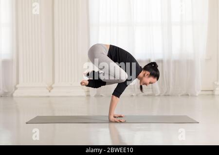 Belle jeune femme asiatique qui s'exerce, fait de l'exercice de yoga, de l'asana de la main, de l'exercice pour les bras et les poignets, pose de Crower Crow, Bakasana Banque D'Images