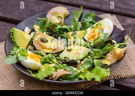 Salade avec légumes, œufs et légumes verts sur table en bois Banque D'Images
