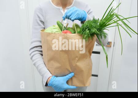 Le volontaire en gants bleus tient des légumes pour le don de nourriture pour aider les pauvres. Donner la boîte avec les aliments Banque D'Images