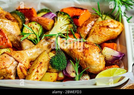 Des cuisses de poulet cuites avec des légumes dans le plat du four. Poulet cuit avec patate douce, courgettes et brocoli. Banque D'Images