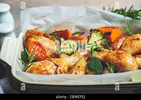 Des cuisses de poulet cuites avec des légumes dans le plat du four. Poulet cuit avec patate douce, courgettes et brocoli. Banque D'Images