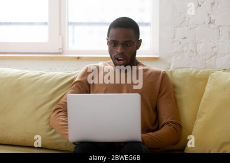 L'ethnicité africaine gars gawp à l'écran d'ordinateur portable se sent choqué Banque D'Images